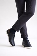Person wearing navy blue pants and black leather shoes on a white background