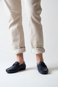 Navy loafers worn with beige pants on a white background