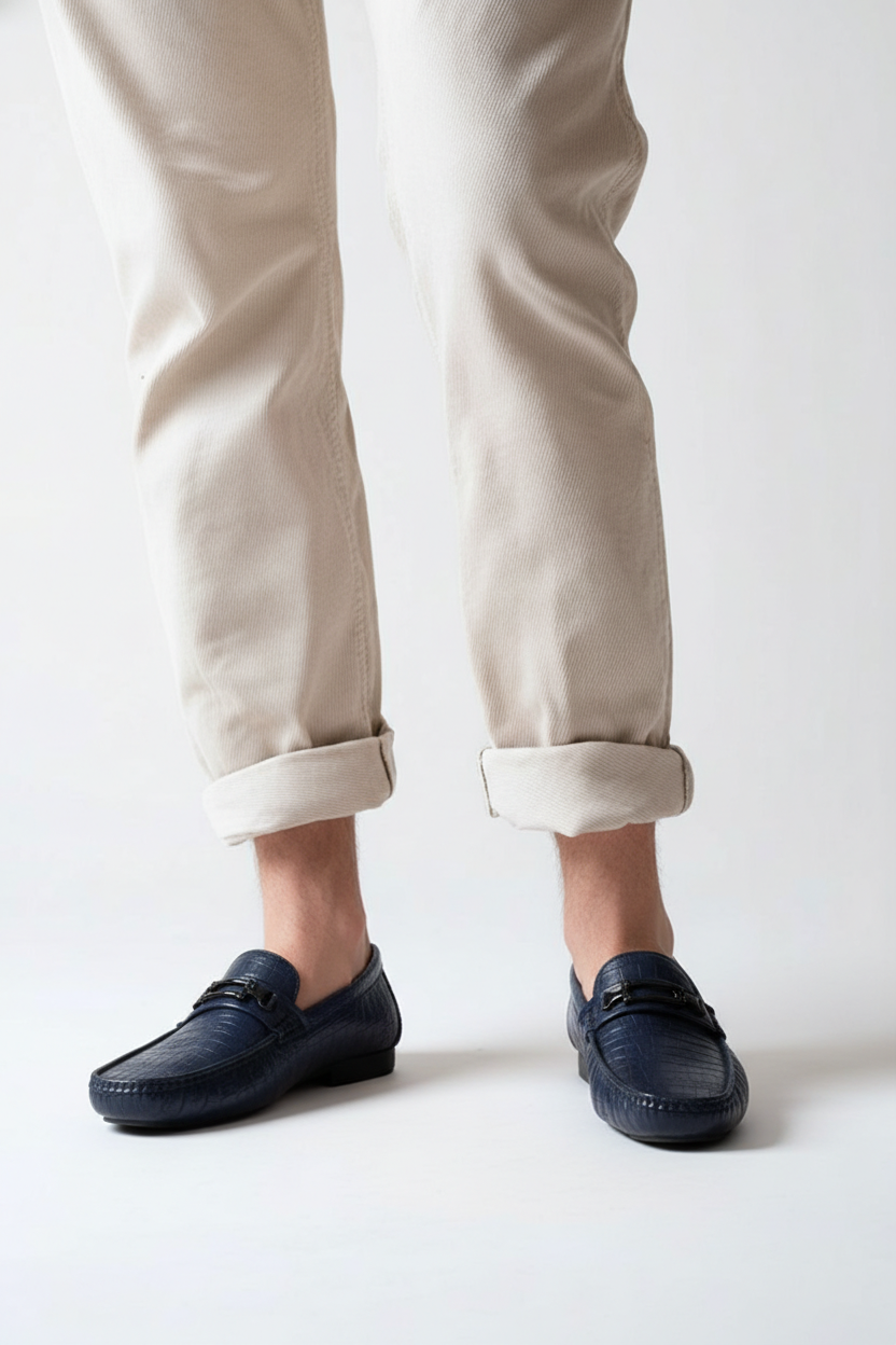 Navy loafers worn with beige pants on a white background