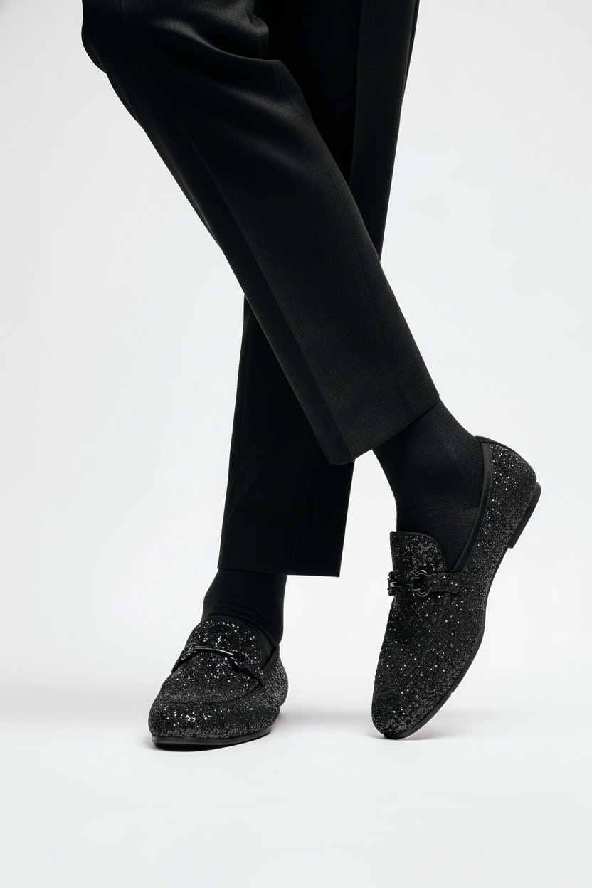 Black glittery loafers worn with black pants on a white background